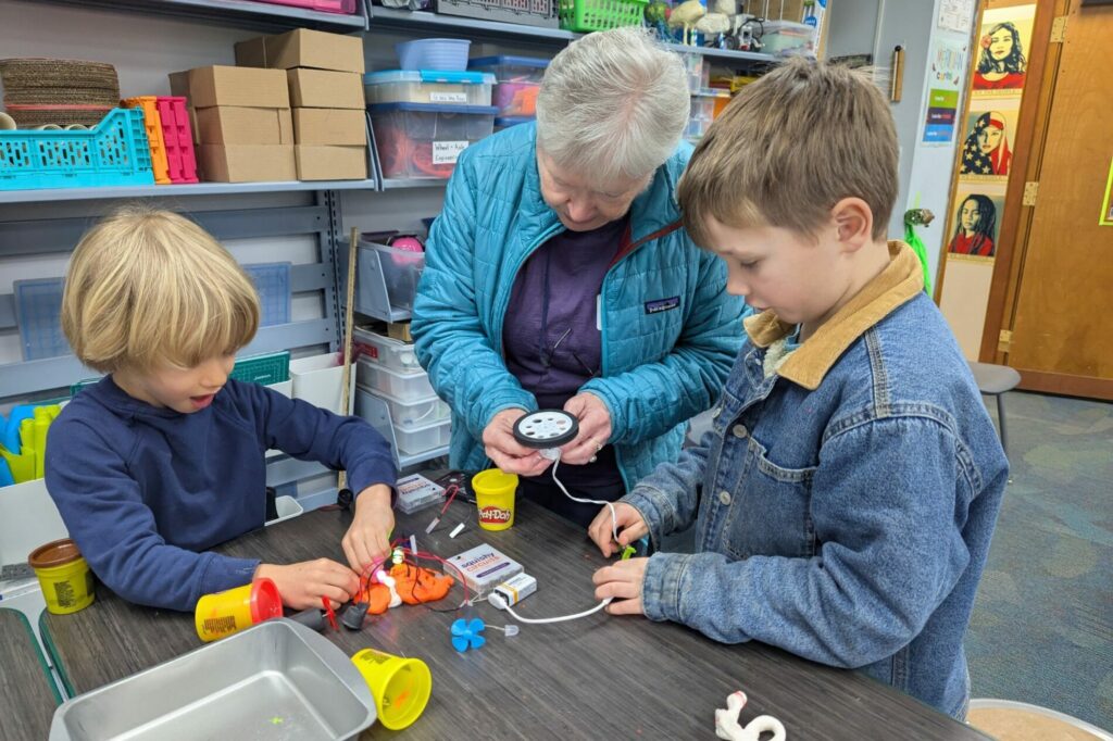 Two students show their grandparent how electrical circuits work.