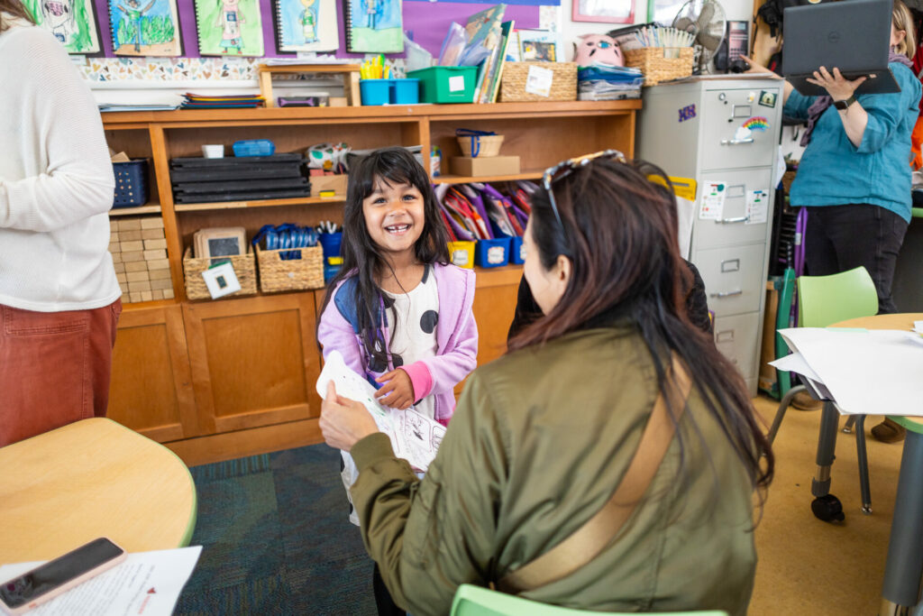 A student showcases her project with joy at The Meridian School, a pre-k and k-5 independent school in Seattle's Wallingford neighborhood.