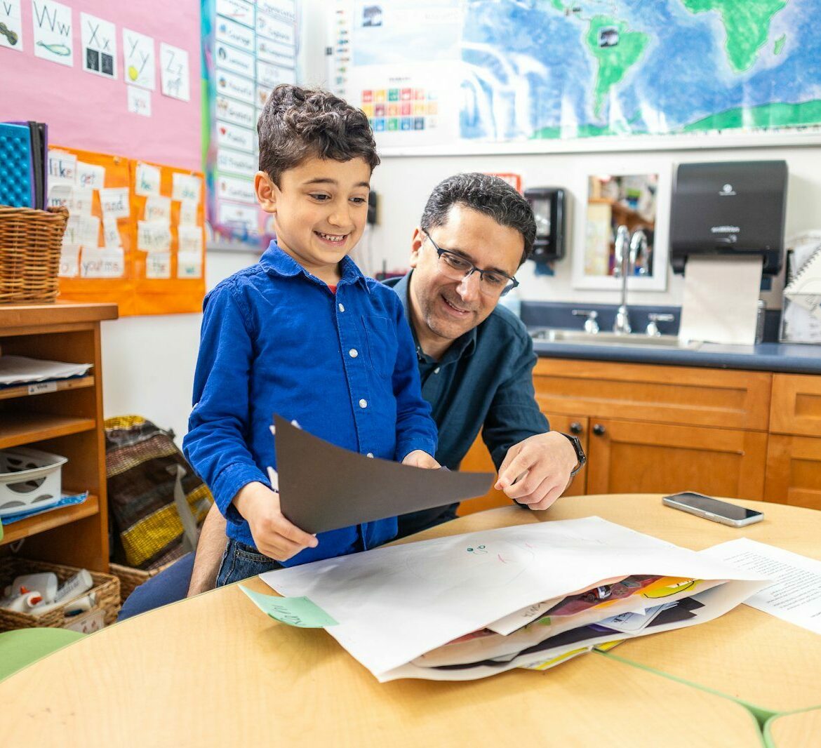 student with teacher smiling at worksheet