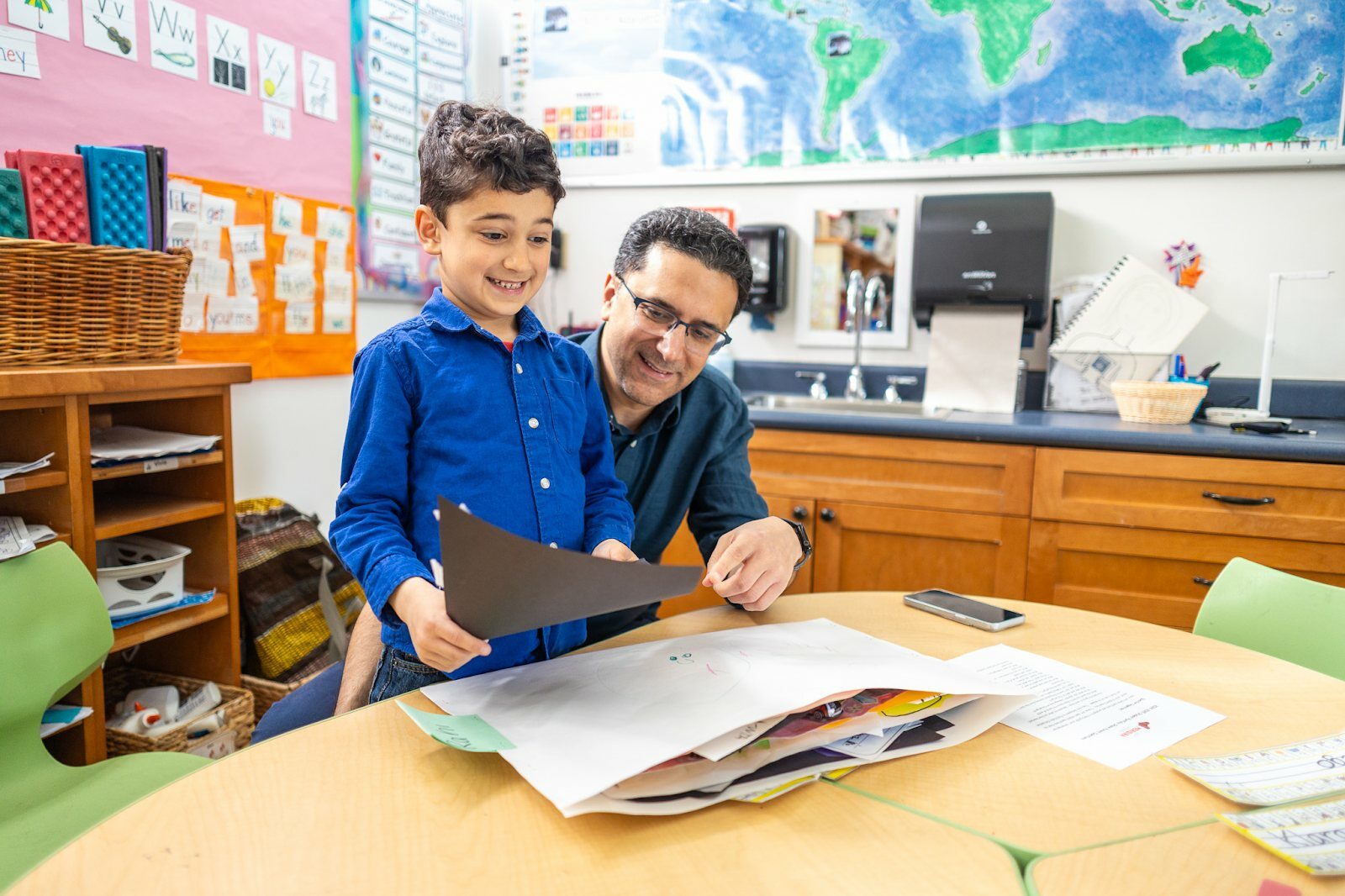 student with teacher smiling at worksheet