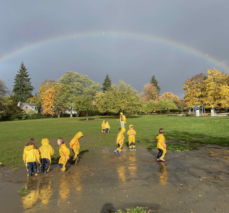 students in rain jackets outside in wet grass