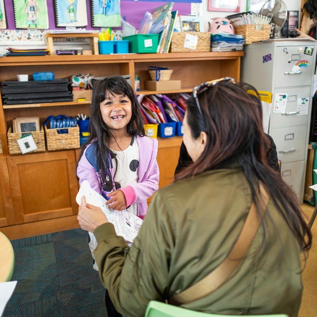 student with teacher smiling at worksheet