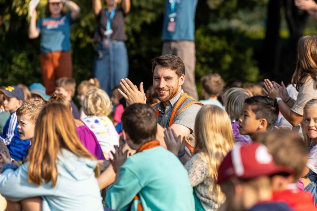 A teacher claps in a crowd of students