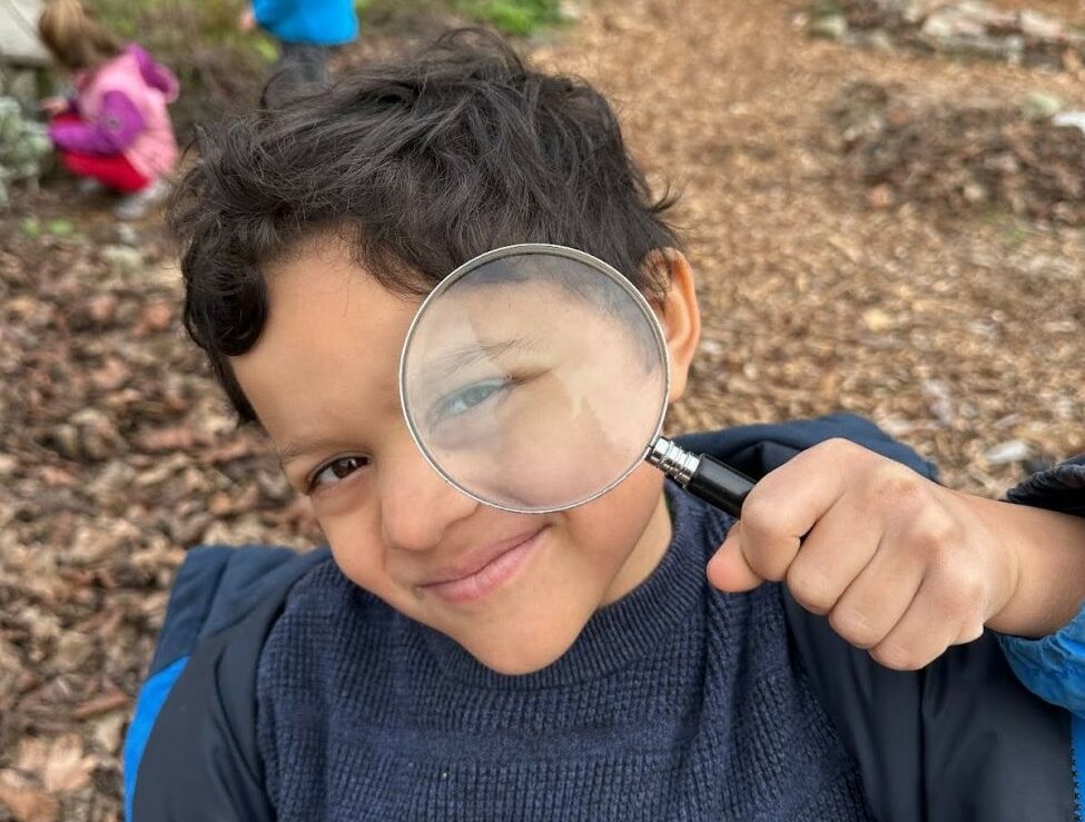 A student from The Meridian School, an independent elementary school in Seattle's Wallingford neighborhood, holds up a magnifying glass inquisitively.