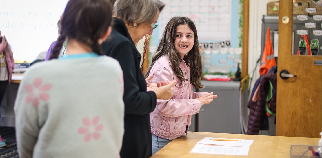 students at desk with teacher