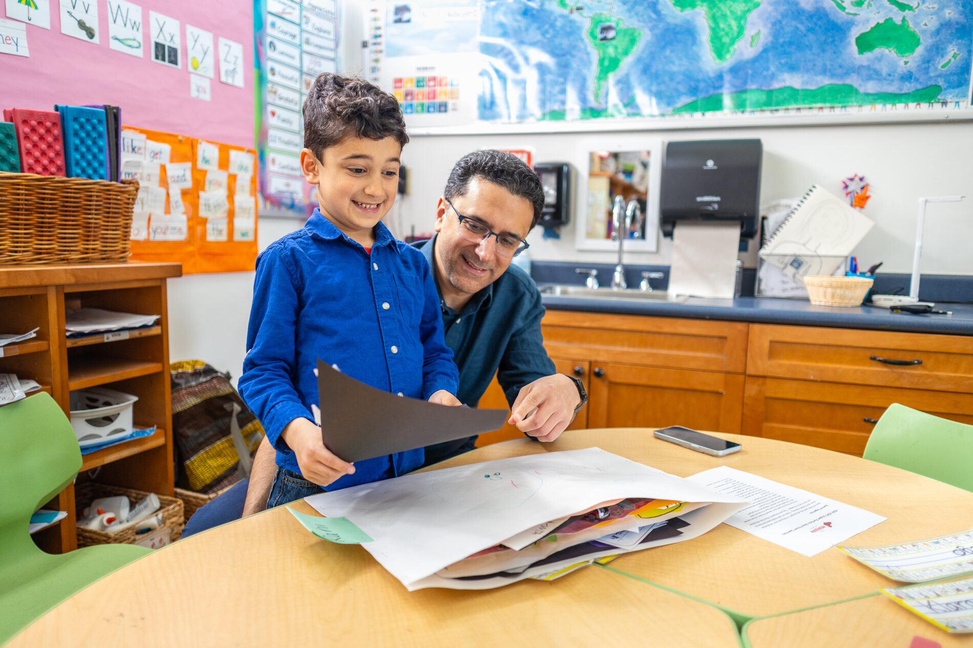 A student from The Meridian School shows his father his school projects in kindergarten. From PreK–5th grade, students present their work at the end of school.
