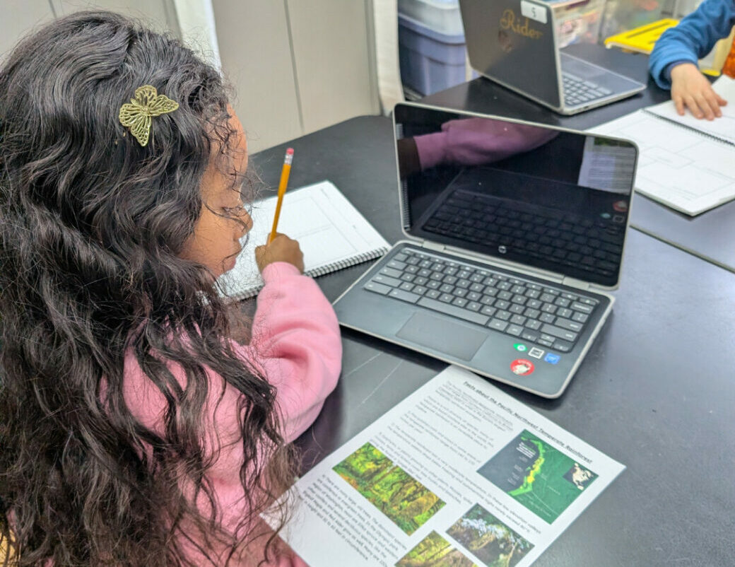 student reading paper with laptop